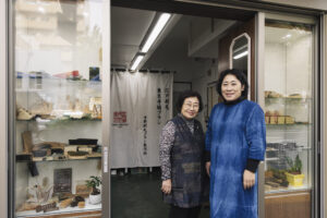 写真上：宇野刷毛ブラシ製作所の三代目の宇野千榮子（左）と、娘の三千代（右）。2024年11月、改装した店舗兼工房の前で。
